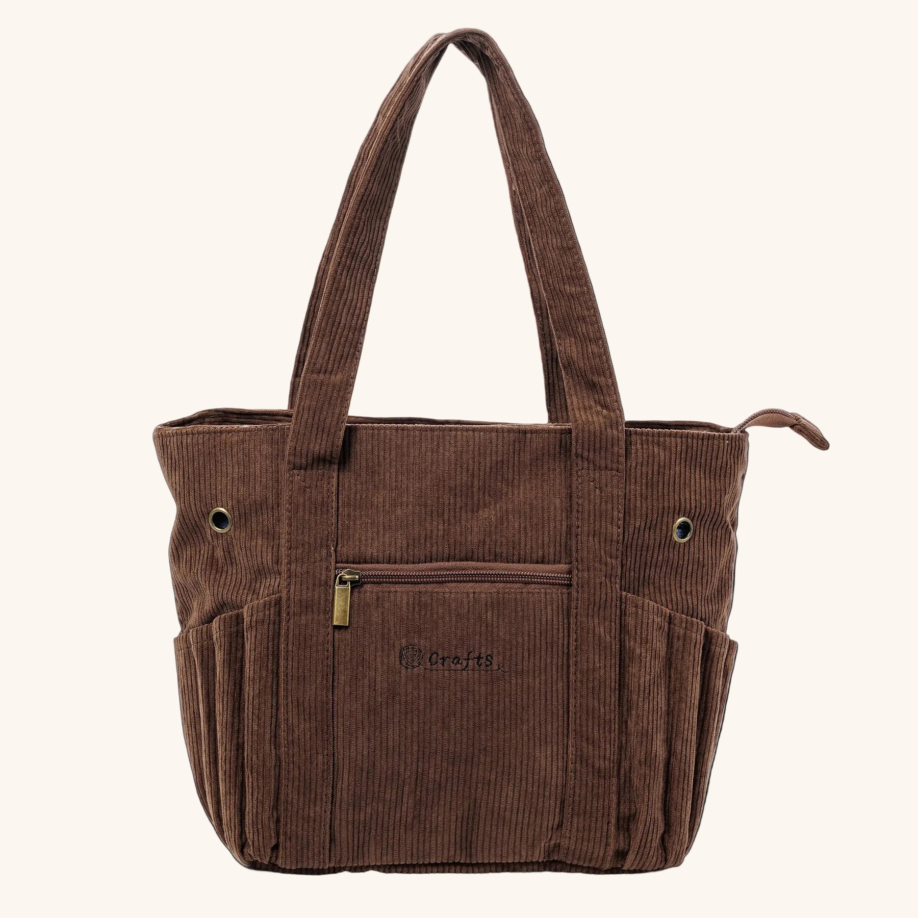 A brown corduroy tote bag with dual shoulder straps, a front zippered pocket, and side pockets, shown against a plain off-white background.